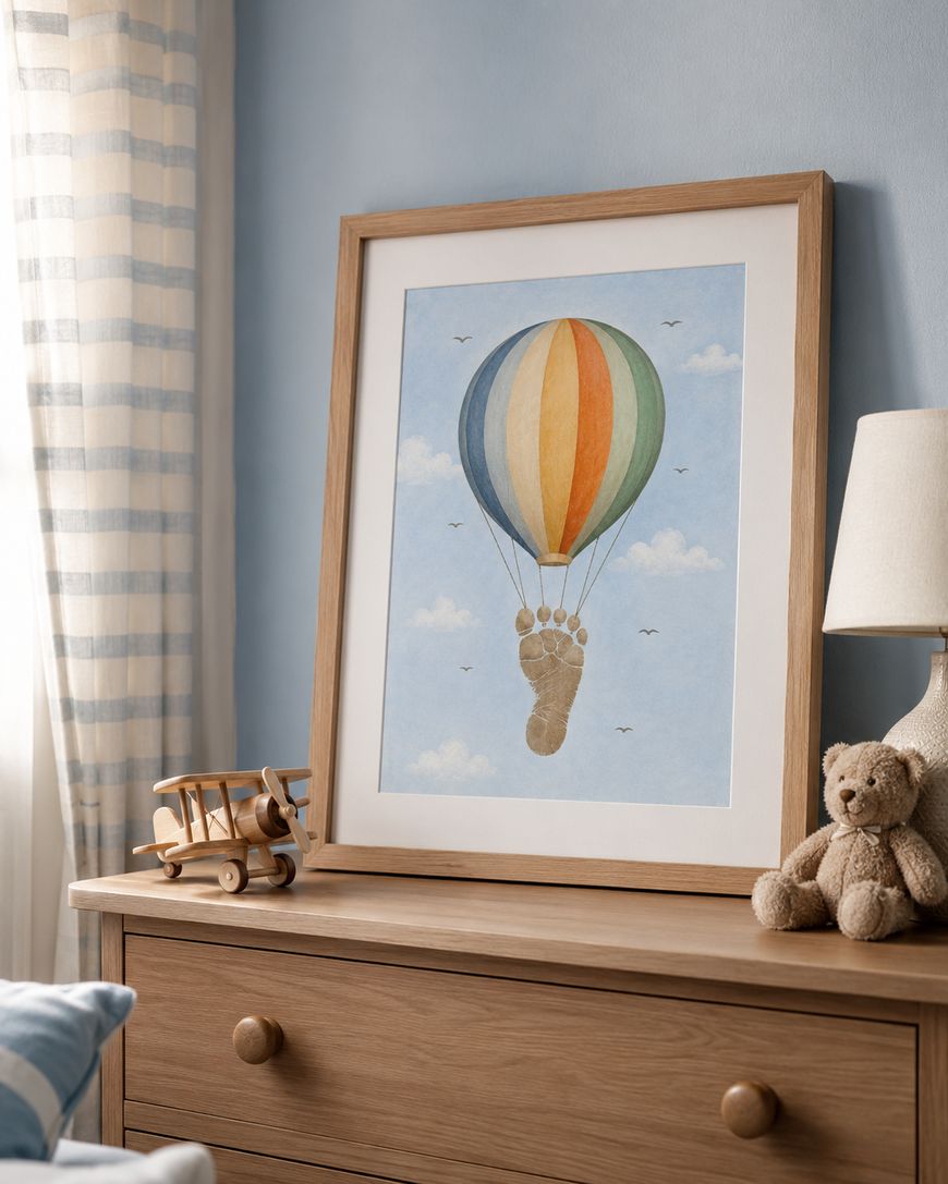 A wooden dresser holds a framed print of a hot air balloon with a footprint as the basket, a toy biplane, and a teddy bear beside a lamp. The background features light blue walls and a striped curtain.