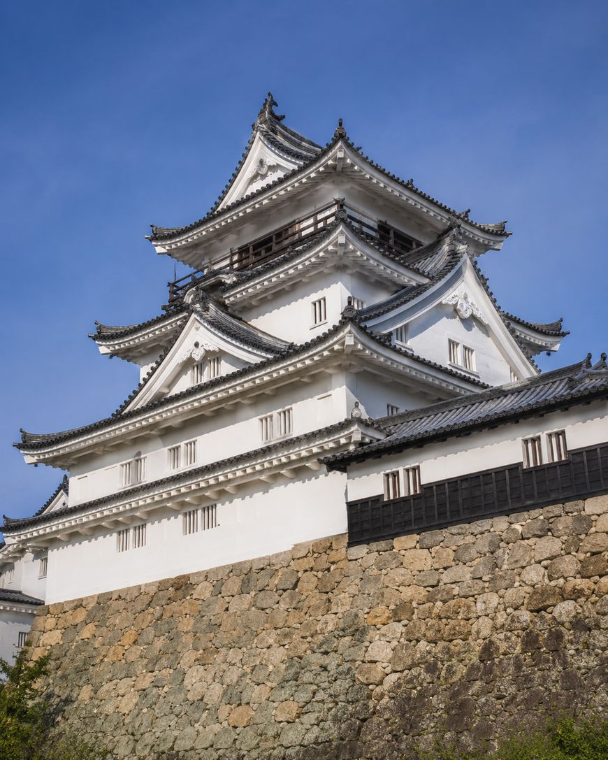 A traditional Japanese castle with white walls and tiled roofs