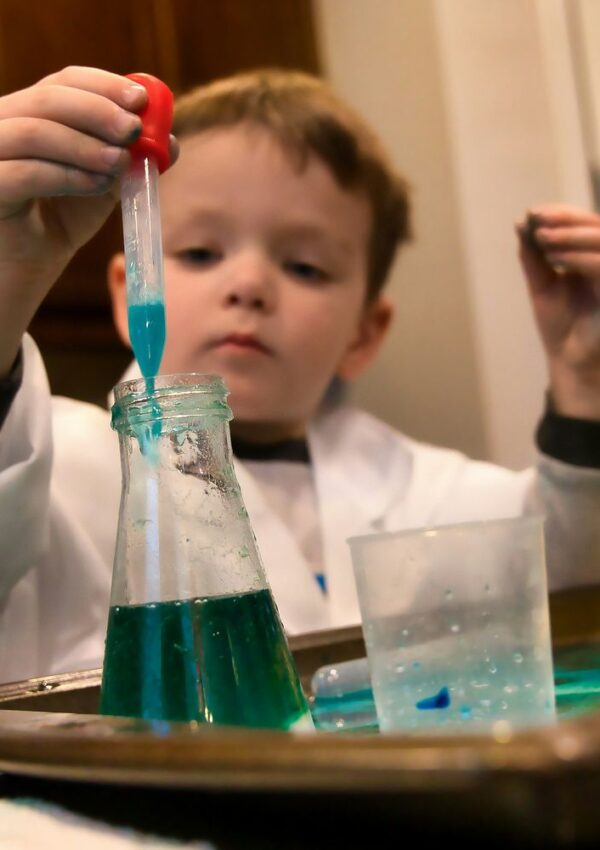 Child holding a red and clear plastic tool during a hands-on eggshell science experiment