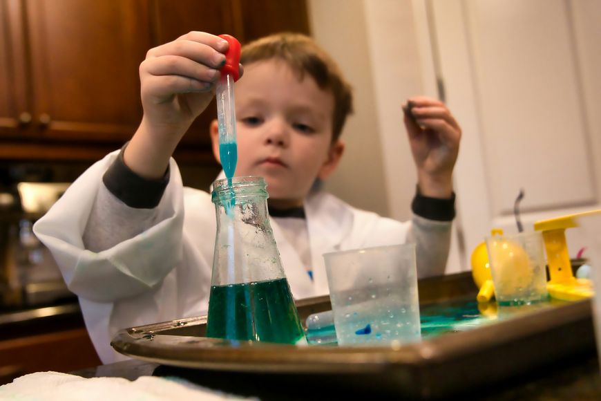 Child holding a red and clear plastic tool during a hands-on eggshell science experiment